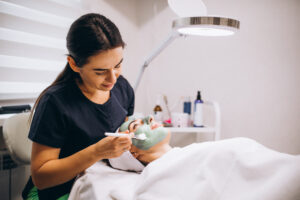 Cosmetologist applying mask on a face of client in a beauty salon