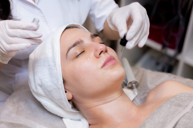 A young beautiful girl lies on the beautician's table and receives procedures with a professional apparatus for skin rejuvenation and moisturizing